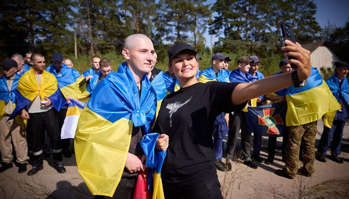 In this handout photograph taken and released by the Ukrainian Presidential Press Service on September 14, 2024, a Ukrainian prisoner of war (POW) poses for a selfie photo with a volunteer following a swap at an undisclosed location in Ukraine. — AFP