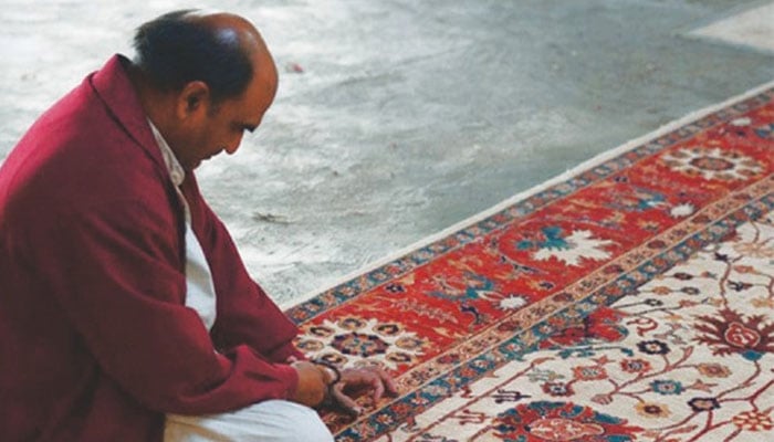 A representational image showing weaver looking at a finished carpet. — AFP/File