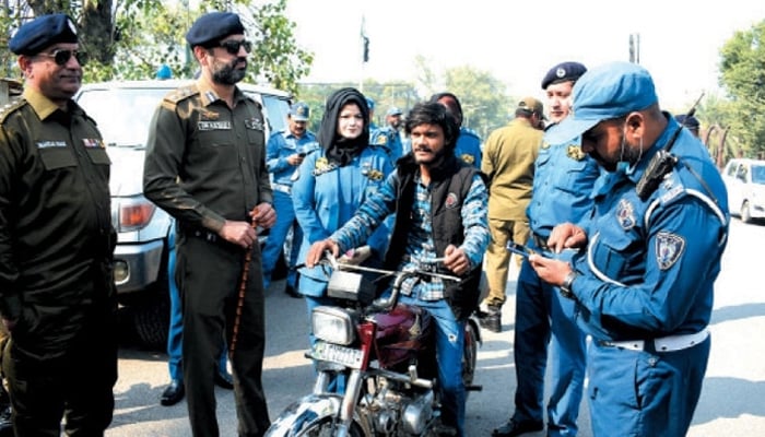 A city warden in Islamabad is cutting the challan of a citizen on bail, on this occasion Punjab police officers and other city wardens are also present in this image. — APP/File