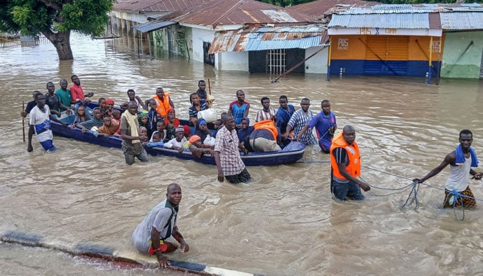 A representational image showing people riding a boat in flood waters in Maiduguri on September 12, 2024. —  AFP