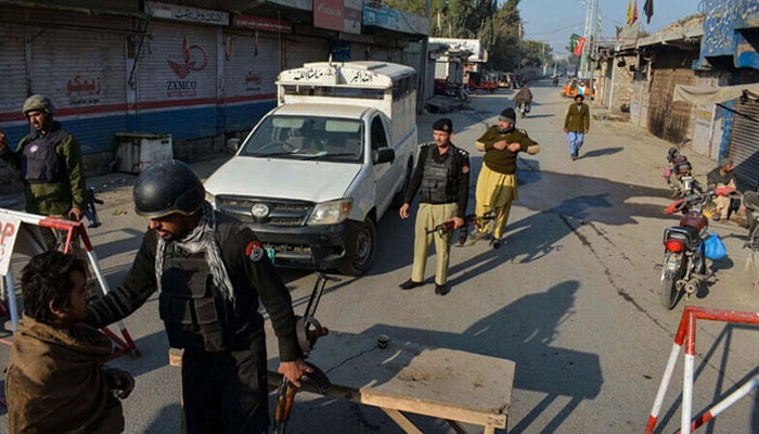 Police stand guard along a road they blocked after militants seized a police station in Bannu on December 19, 2022. — AFP