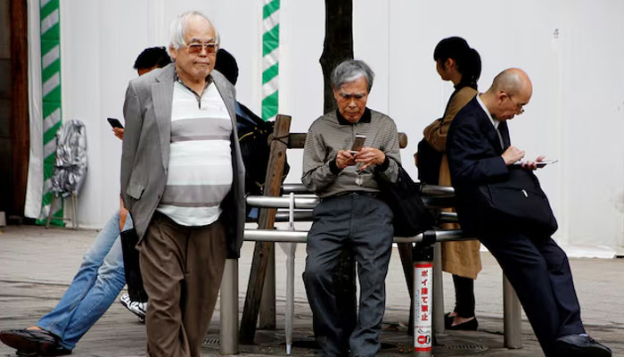 An elderly man uses a mobile phone in front a station in Tokyo, Japan, October 11, 2018. — Reuters