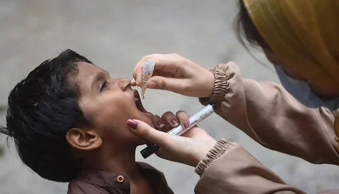 A health worker administers polio drops to a child during a door-to-door vaccination campaign in Karachi on August 7, 2023. — AFP