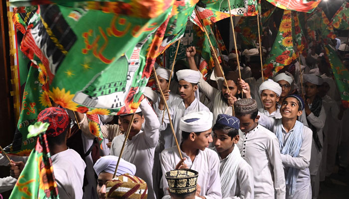 People carry religious flags as they take part in a rally to celebrate on the eve of Eid Milad-un-Nabi (PBUH) in Lahore on September 16, 2024. — AFP