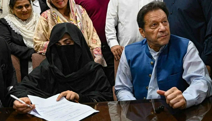 PTI founder Imran Khan (right) pictured along with with his wife Bushra Bibi (left), looks on as she signs surety bonds for bail in various cases, at a registrar office in the Lahore High Court on July 17, 2023. — AFP