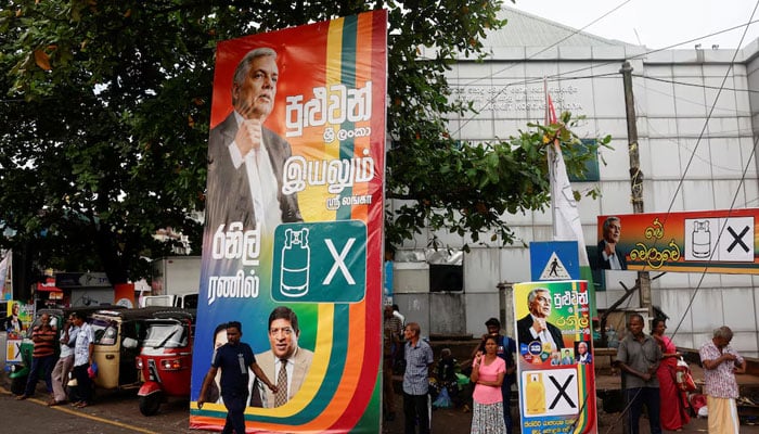 People walk near the posters of Sri Lankas president Ranil Wickremesinghe before his final rally at a residential area for the upcoming presidential election, scheduled for September 21, in Colombo, Sri Lanka September 18, 2024. — Reuters