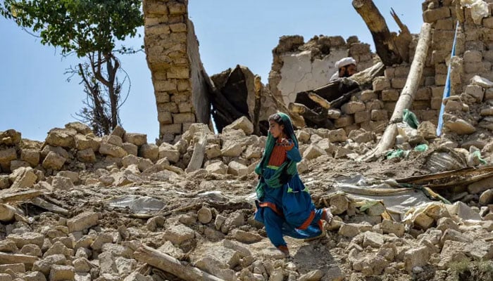 A child walks amidst the rubble of damaged houses following a powerful earthquake in Bernal district, Paktika province on June 23, 2022. — AFP