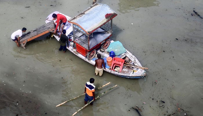 Flood-affected residents move their belongings on a boat following heavy monsoon rains in the Indian city of Prayagraj. — AFP/File