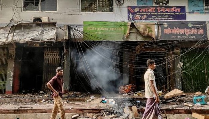 People walk past vandalized shops following a clash between a tribal group and settlers in Rangamati, in Bangladeshs Chittagong Hill Tracts on Friday September 20, 2024 — AFP