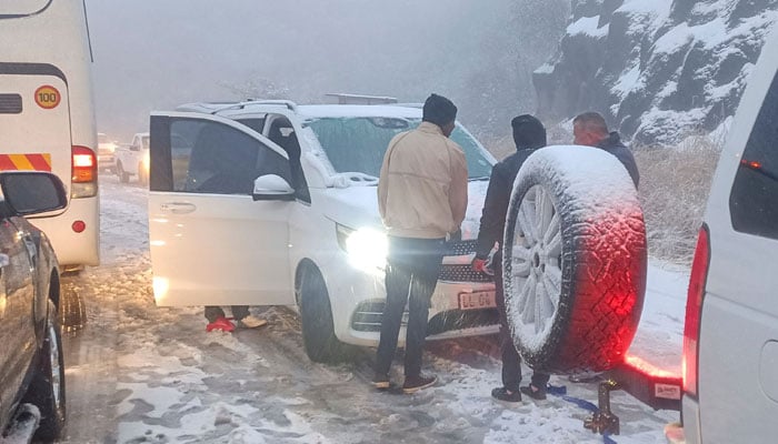 People attempt to free a car stuck in heavy snowfall on Oliviershoekpass near Harrismith on September 20, 2024. — AFP