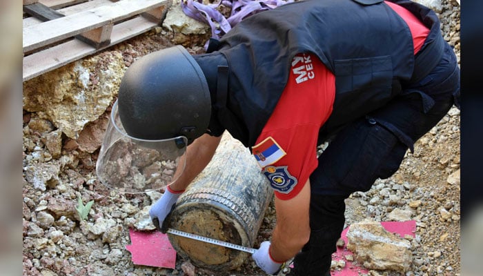 A handout photo distributed on September 22, 2024, by the Ministry of the Interior of Serbia, shows a special police unit officer near an unexploded 300-kilo WWI artillery round at a construction site near the Serbian Parliament in Belgrade. — AFP