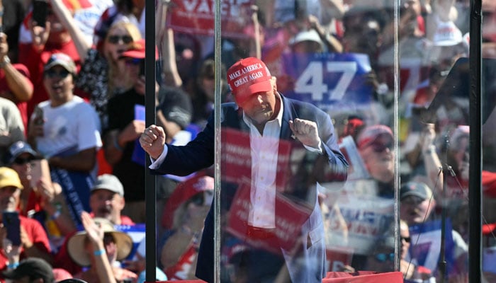 Former US President and Republican presidential candidate Donald Trump dances behind bulletproof glass as he concludes his remarks during a campaign rally at the Aero Center in Wilmington, North Carolina, September 21, 2024. — AFP