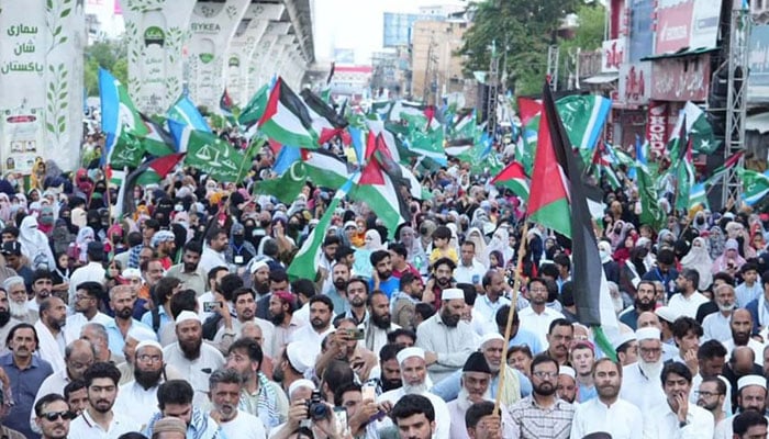 A representational image showing JI supporters holding party and Palestine flags during a demonstration. — Facebook@jiislamabad/File