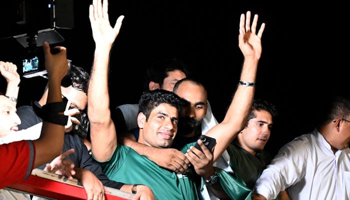 Arshad Nadeem, Pakistan’s first Olympic gold medalist athlete in the mens javelin, waves from the roof of a vehicle to fans who gathered to welcome him on his arrival, outside the Allama Iqbal International Airport, in Lahore on August 11, 2024. — Reuters