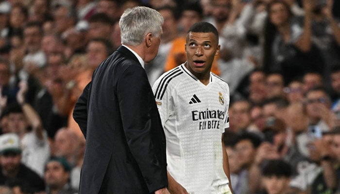 Real Madrids French forward #09 Kylian Mbappe talks with Real Madrids Italian coach Carlo Ancelotti during the Spanish league football match between Real Madrid CF and Deportivo Alaves in Madrid on September 24, 2024. — AFP