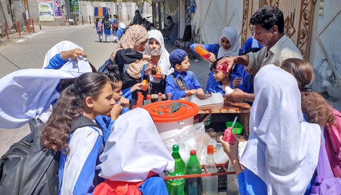 School children busy in purchasing ice balls from street vendor during hot day at the Committee Chowk in Rawalpindi on May 20, 2024. — APP