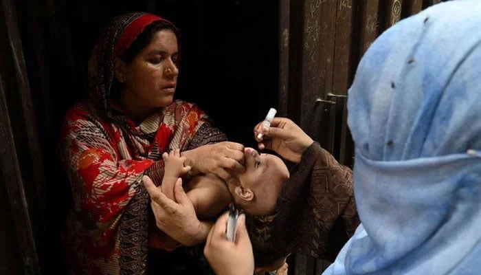 A health worker administers polio vaccine drops to a child during a polio vaccination campaign at a slum area in Lahore on August 2, 2021. — AFP