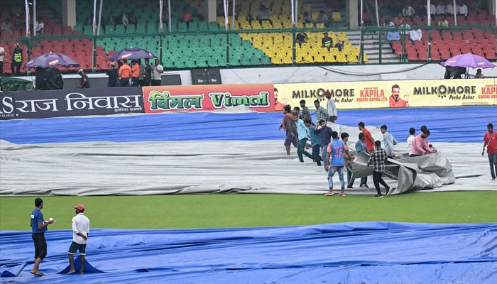 Groundsmen cover the field as rain delays the start of the second day play of the second Test cricket match between India and Bangladesh at the Green Park Cricket Stadium in Kanpur on September 28, 2024. — AFP