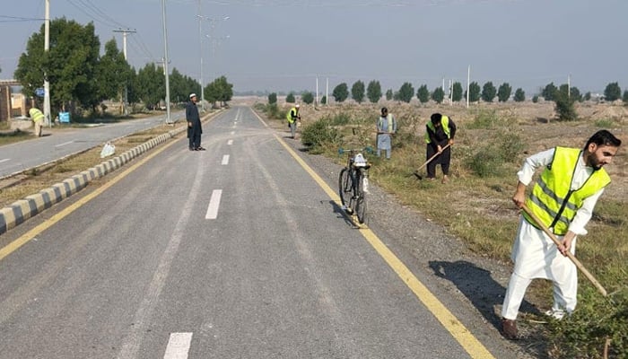 This representational image shows workers works alongside the road released on November 12, 2023. — Facebook/Peshawar Development Authority