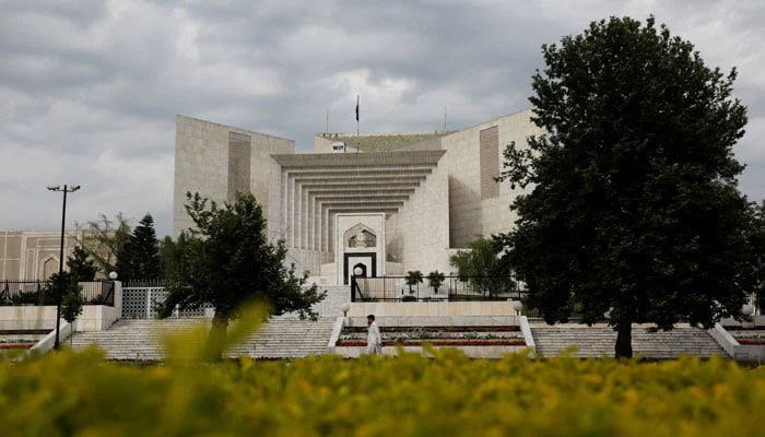 A man uses his mobile phone as he walks past the Supreme Court building in Islamabad on May 13, 2023. — Reuters