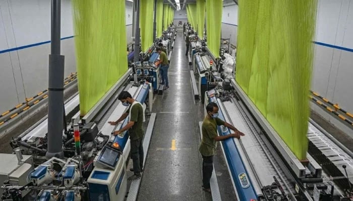 A worker operates a machine preparing fabric at a textile mill in Lahore on July 20, 2023. — AFP