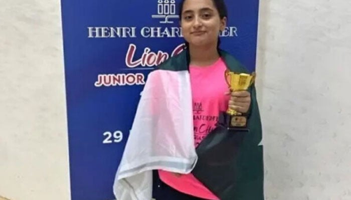 Pakistani squash player Mahnoor Ali poses with the national flag and trophy in this undated photo. — State media/File