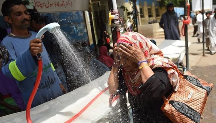 A volunteer showers a woman with water during a heat wave in Pakistan. — AFP/File