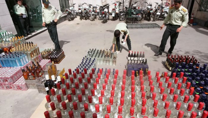 Iranian police prepare to destroy confiscated bottles of alcohol in Tehran. — AFP/file