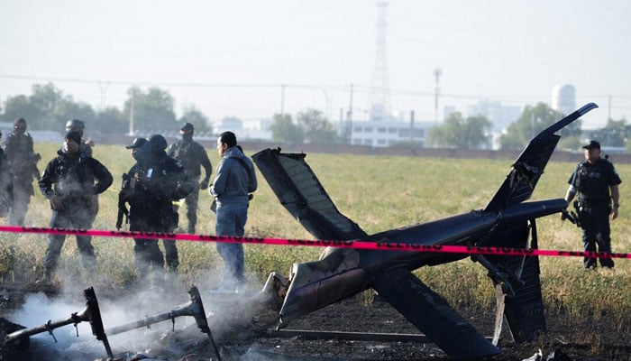 A representational image of security personnel standing around a helicopter crash. — Reuters/File