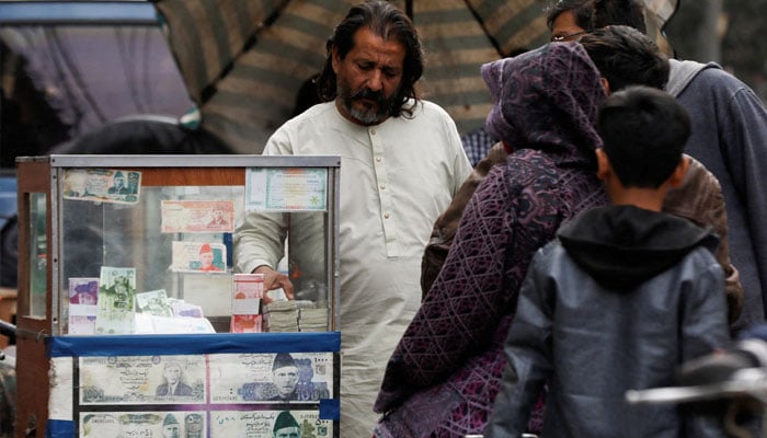 A currency broker stands near his booth, which is decorated with pictures of currency notes, while dealing with customers, along a road in Karachi, Pakistan January 27, 2023. — Reuters