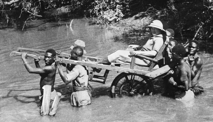 A file photo taken in Senegal, then a French colony, in the 1930s shows a European being carried through a river by African porters in a sedan chair — AFP