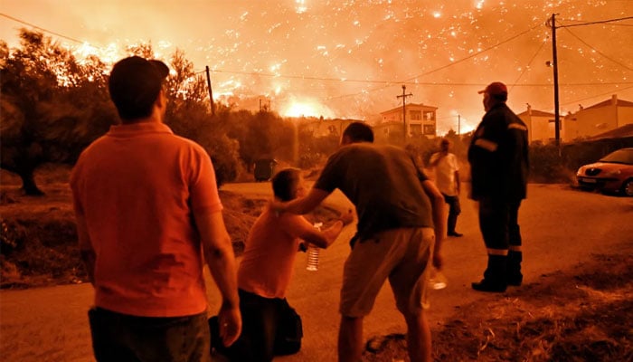 A resident reacts as a wildfire, fanned by strong winds, approaches the village of Ano Loutro, some 131 kilometres (81 miles) west of Athens, Greece, in the region of Corinthia . — AFP