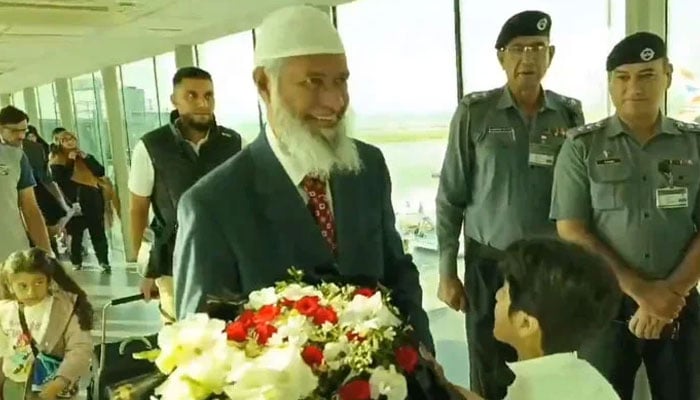 Islamic scholar and public speaker Dr Zaik Naik is greeted with a bouquet of flowers upon his arrival at the Islamabad airport on September 30, 2024. — Screengrab via X/@asadnasir2000