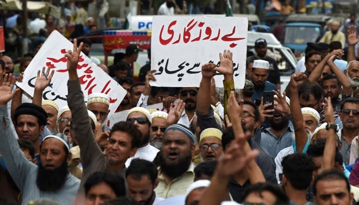 A trader holds a placard reading prevent unemployment from rising during a protest at a street in Karachi on August 23, 2023.—AFP/File