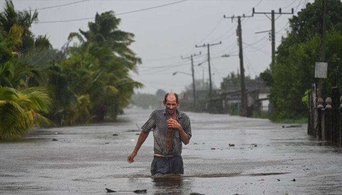 A person seen walking through water after a cyclone. — AFP/file