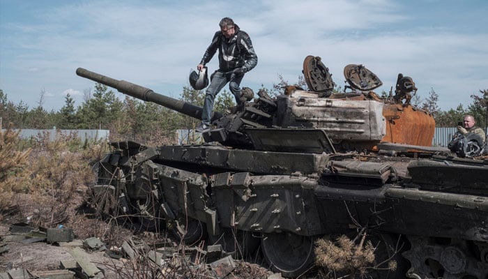 A man walks atop of a destroyed Russian tank, amid Russias invasion of Ukraine, in the Kyiv region, Ukraine, April 7, 2022. — Reuters