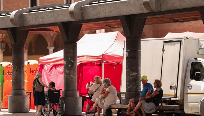 Elderly people take shelter from the sun at a bus station in Forli, Italy, July 19, 2023. — Reuters