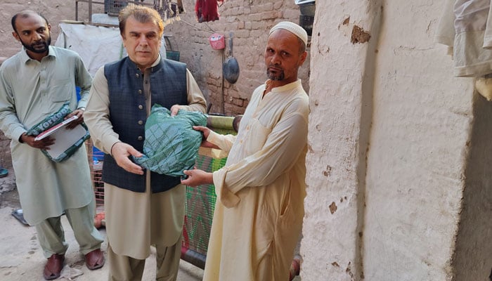 Commissioner, Peshawar Division, Riaz Khan Mahsud handing a mosquito net to a citizen in Peshawar on Oct 4, 2024. — Facebook/ Commissioner Peshawar Division, Peshawar