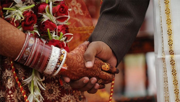 A bride and groom hold hands. — AFP/File