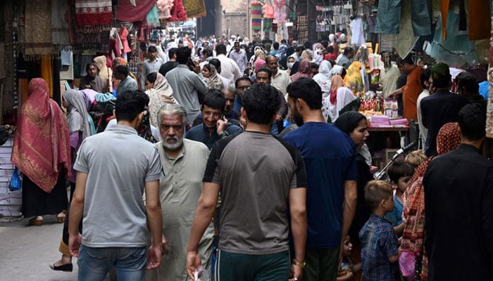 A representational image showing people walking through a market in Lahore. — AFP/File