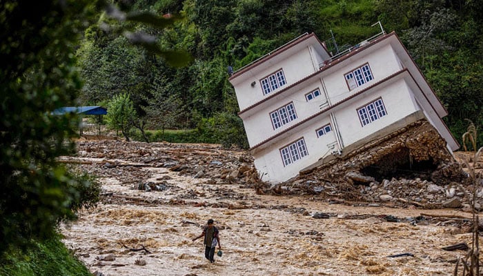 A man wades through the waters in the affected area of monsoon flooding in Roshi village of Nepals Kavre district on September 30, 2024. — AFP