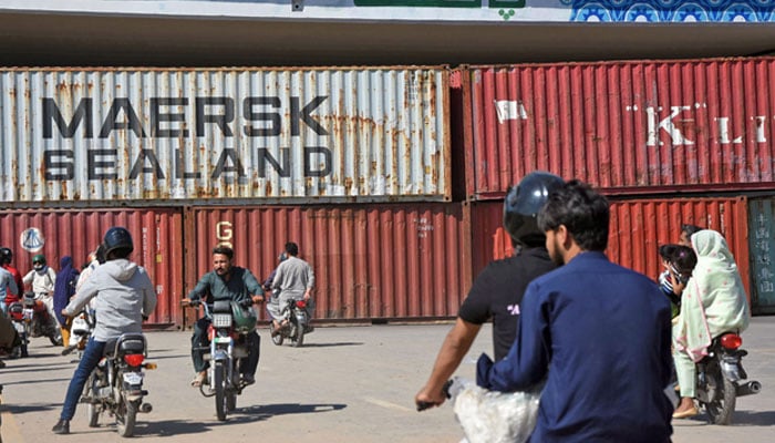 Commuters look at containers placed to block a road in Islamabad on October 6, 2024. — Online