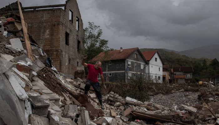 A man walks over a destroyed house after floods and landslides in a village of Trusina, Bosnia and Herzegovina, October 6, 2024. — Reuters