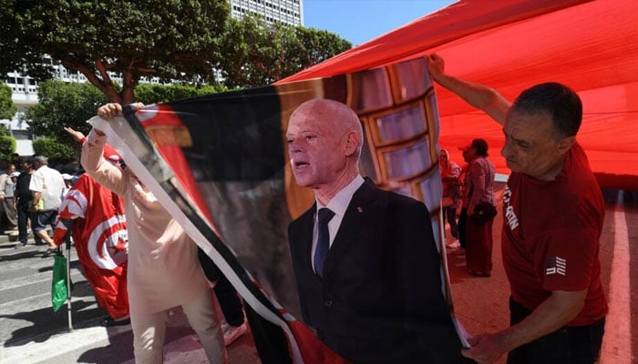 Supporters of Tunisian President Kais Saied ready a portrait for display during a public holiday in July .—AFP/file