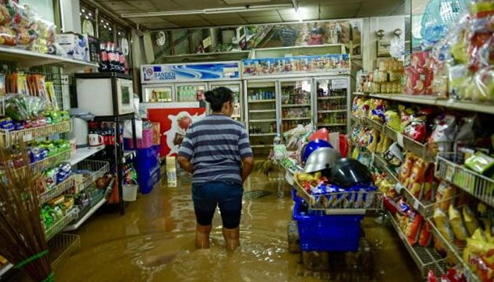 A resident wades through a flood waters inside a convenience store in Chiang Mai, on Sunday. — AFP/file