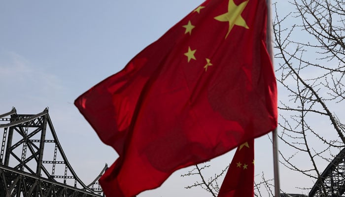 A Chinese national flag flutters near the Friendship Bridge and Broken Bridge over the Yalu River, which separates North Koreas Sinuiju from China, in Dandong, Liaoning province, China April 21, 2021. — Reuters