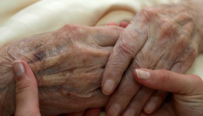 A young carer holds the hands of an elderly woman in a residential home for the elderly in Planegg near Munich June 19, 2007. — Reuters