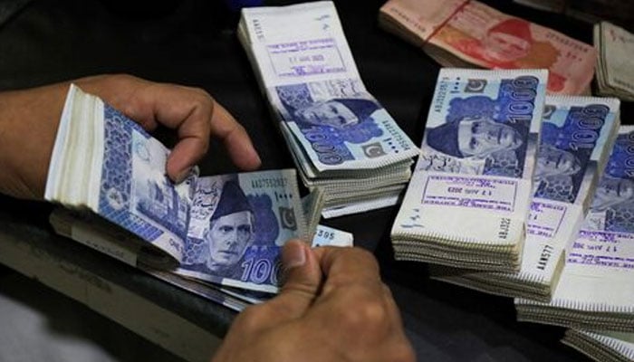 An employee counts Pakistani rupee notes at a bank in Peshawar on August 22, 2023. — Reuters