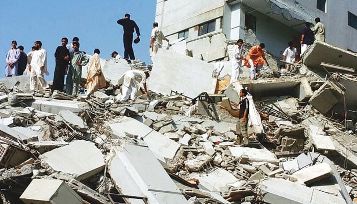 An undated picture showing people walk over rubble after the disastrous 7.6 magnitude earthquake shook northeast Pakistan on October 8, 2005. — AFP/File