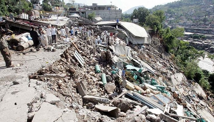 An undated picture shows people walking over rubble after the disastrous 7.6 magnitude earthquake shook northeast Pakistan on October 8, 2005. — Reuters/File